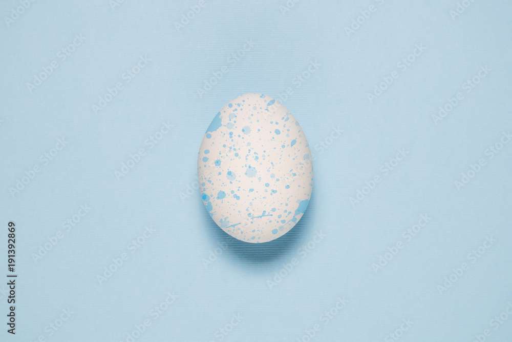 Flat lay of Easter egg with blue stains on pale blue background Flat lay of Easter egg with blue stains on pale blue background