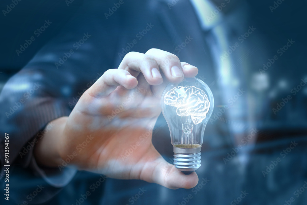 Businessman show a light bulb with a brain that light up. - obrazy, fototapety, plakaty 