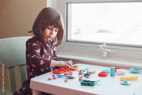 Portrait of cute white Caucasian preschooler girl playing plasticine playdough indoors at home. Early creativity brain development concept. Children activity. Fine motor skills.