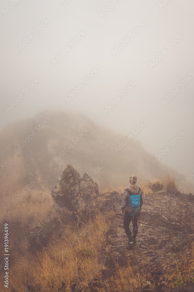 Woman hiker on the cobbled misty path on the mountain crest on Santo Antao island, Cape Verde Woman hiker on the cobbled misty path on the mountain crest on Santo Antao island, Cape Verde