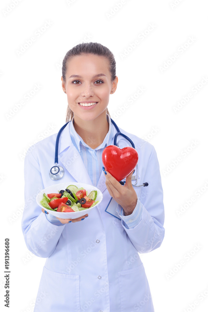 Portrait of a beautiful woman doctor holding a plate with fresh vegetables and red heart. Woman doctors. Portrait of a beautiful woman doctor holding a plate with fresh vegetables and red heart. Woman doctors.