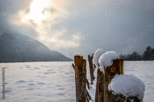 Winterlandschaft: Beschneites Feld und aus den Wolken herausbrechende Sonne