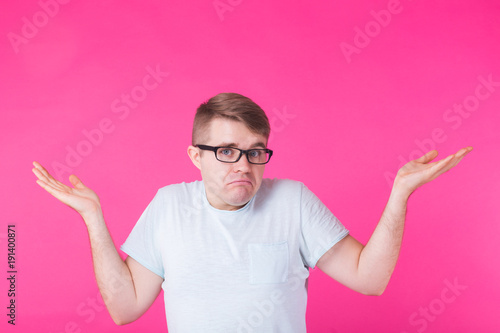 Tableau sur toile Doubtful caucasian man with gestures in uncertainty, confused and puzzled, looks directly into camera, isolated over pink background
