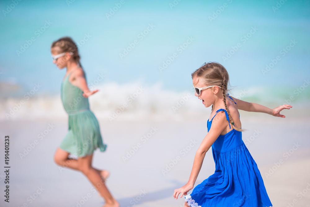 Adorable little girls have a lot of fun on the beach. Two beautiful kids running and splashing in shallow water Adorable little girls have a lot of fun on the beach. Two beautiful kids running and splashing in shallow water