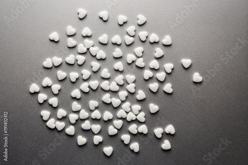 A lot of white medicine pills in the form of hearts on a grey