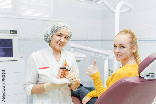 Doctor dentist and happy female patient show thumb up at dental clinic
