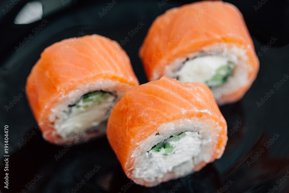 Roll philadelphia made of fresh salmon and cream cheese inside on black plate. Asian traditional food Roll philadelphia made of fresh salmon and cream cheese inside on black plate. Asian traditional food