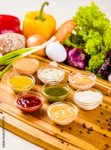 Different sauces assortment on wooden cutting board photo