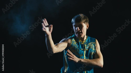 Young man training barehanded wushu against black background photo