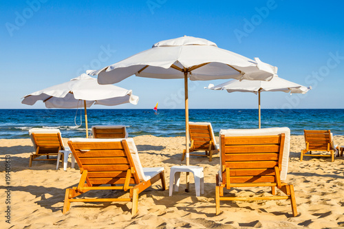 Coastal landscape - Beach umbrellas and loungers on the sandy seashore, the Kavatsi bay near city of Sozopol in Bulgaria