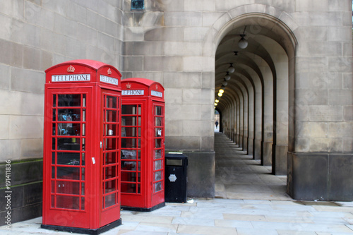 Two traditional red telephone boxes and archway