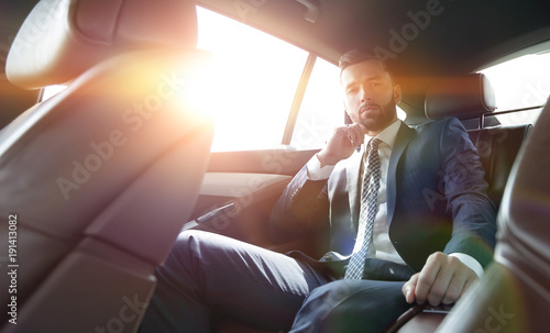 businessman talking on the phone while sitting in the back seat of his car © ASDF