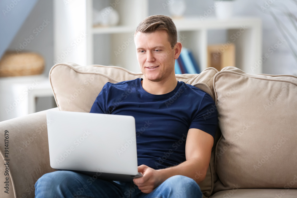 Young man using laptop on couch indoors Young man using laptop on couch indoors