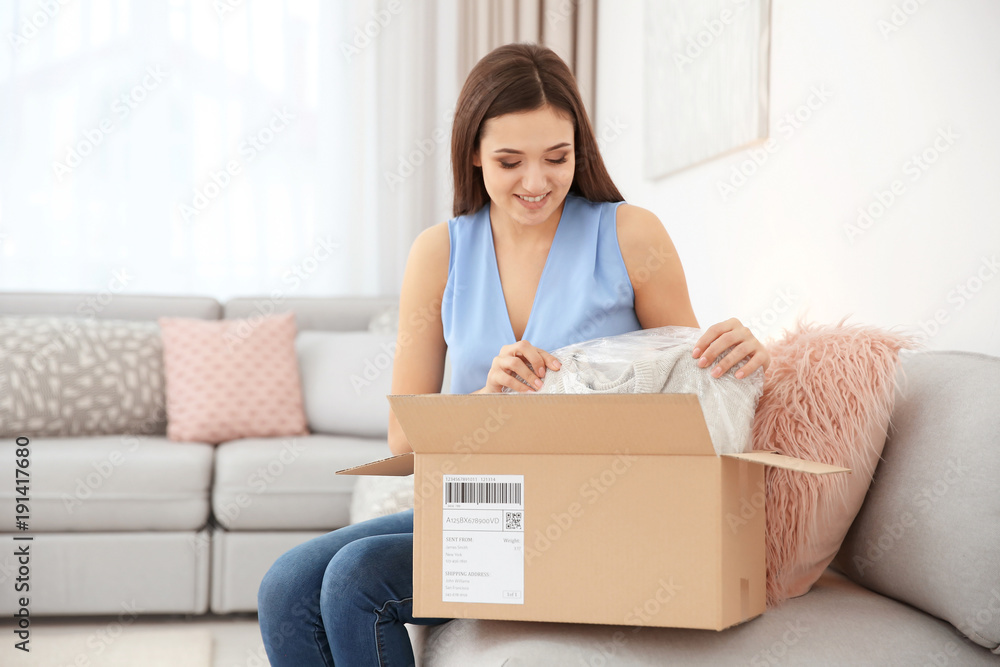 Young woman opening parcel indoors Young woman opening parcel indoors