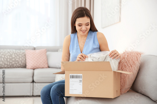 Young woman opening parcel ...