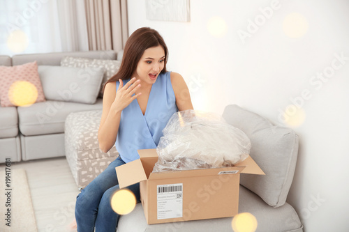 Young woman opening parcel indoors