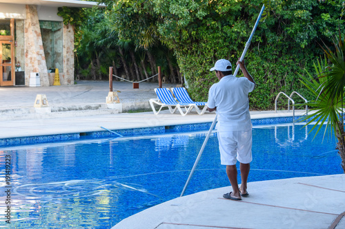 A man, personnel cleaning the pool at a tropical resort.