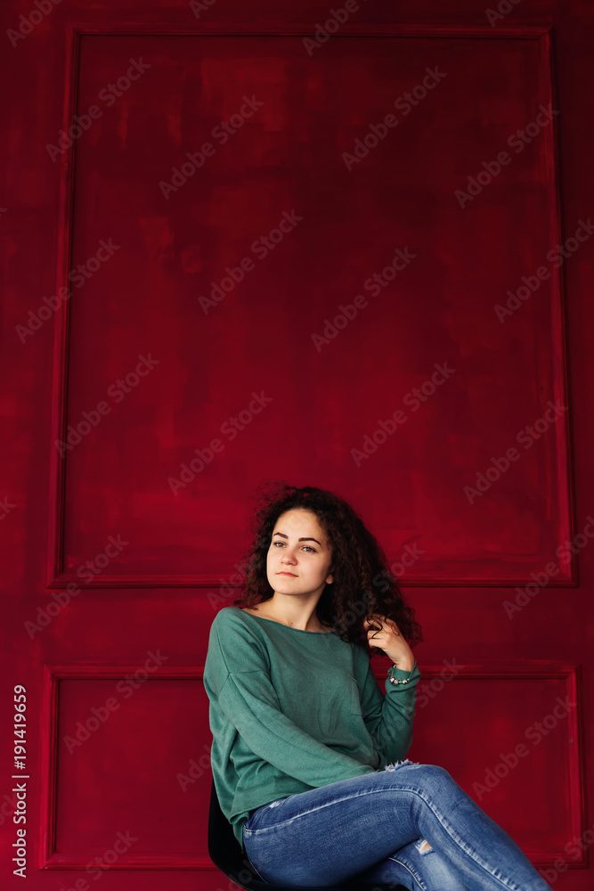 A girl with a serious face sitting on a chair in a red room A girl with a serious face sitting on a chair in a red room