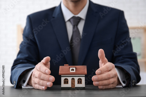 Real estate agent with house model at table. Insurance concept