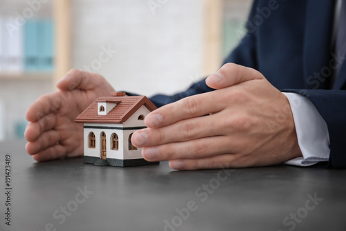 Real estate agent with house model at table. Insurance concept