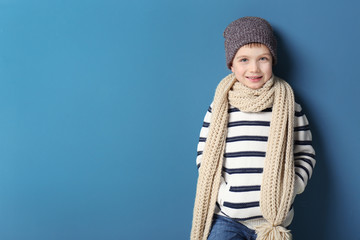 Cute little boy in warm clothing on color background. Ready for winter vacation