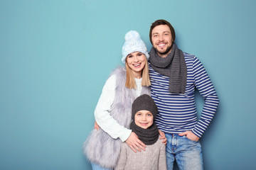 Happy family in warm clothing on color background. Ready for winter vacation
