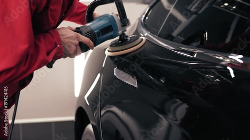 Automechanic polishing a black new car. Cleaning the new vehicle. photo