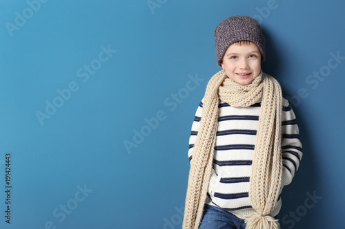 Cute little boy in warm clothing on color background. Ready for winter vacation