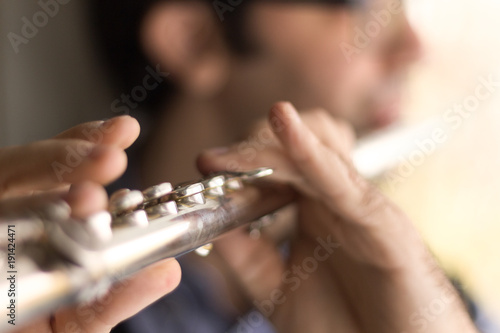 Male hands playing a transverse flute.