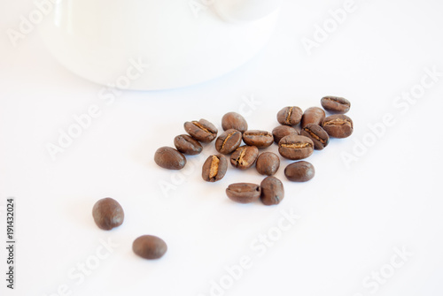 Roasted coffee beans places near enamel pot on white background