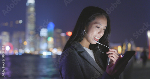 Woman talk to cellphone with earphone at Hong Kong at night