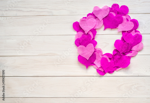 valentine day concept. a wreath decorated with purple and pink crepe paper hearts with copy space on white wooden background