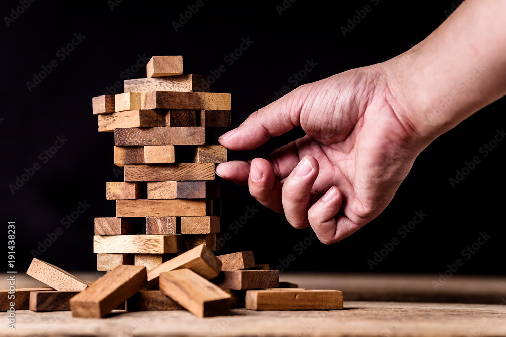 hand pull piece of wood block out of stack risk and construction ideas concept hand pull piece of wood block out of stack risk and construction ideas concept