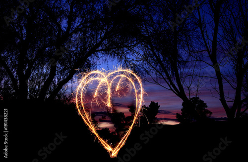 Sparkling heart at sunset background. © CellarStorm