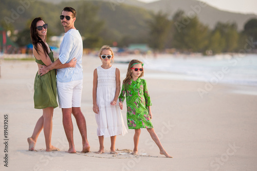 Happy family with kids walk on the beach at sunset