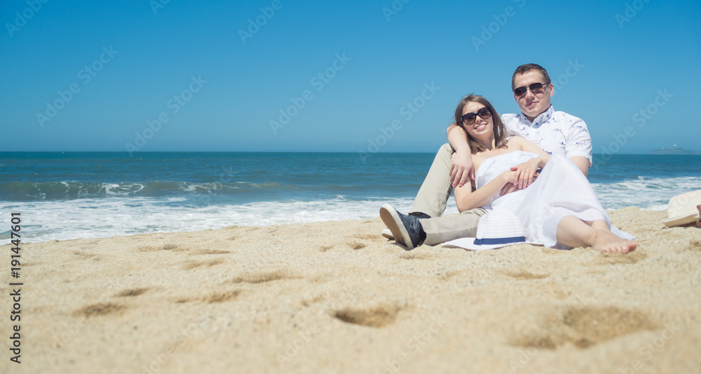 Young romantic couple sitting on the beach