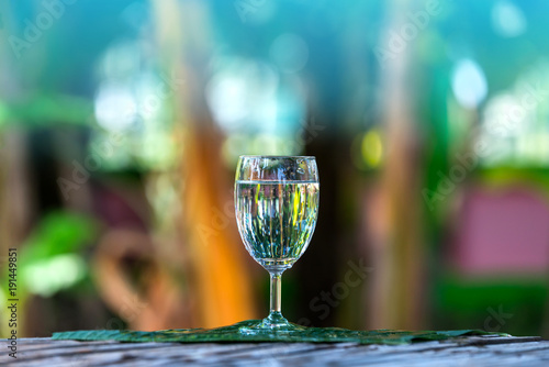 Drink water pouring in to glass over sunlight and natural green background.Select focus blurred background.Photo select focus.