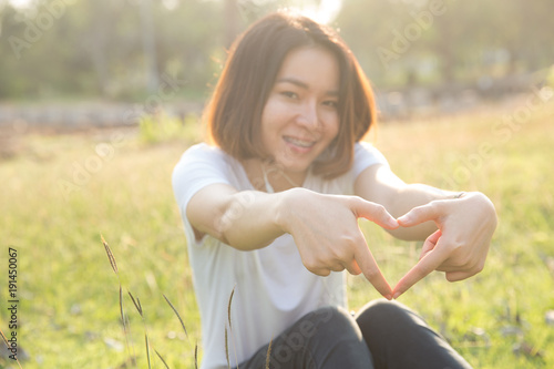 Cute Thai asian girl love heart shape with her hands in sunshine.