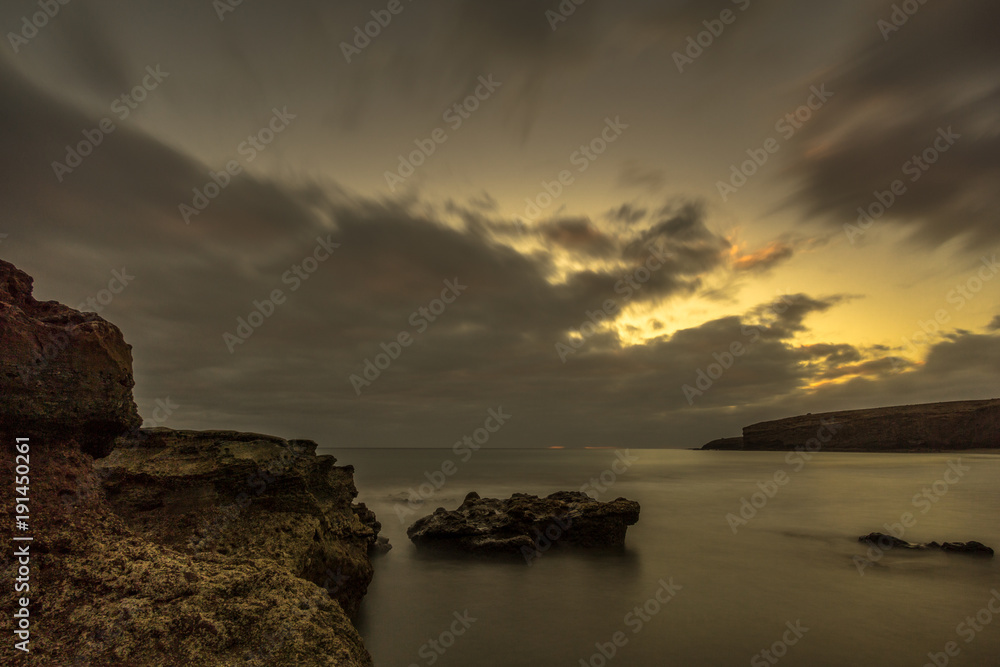 Beach with big lava stones at sunset. Canary Islands and long exposure