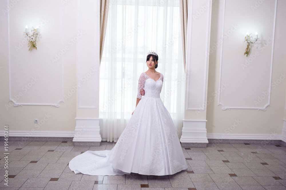 Beautiful bride in a wedding dress white interior Beautiful bride in a wedding dress white interior