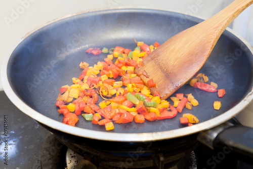 Frying pan with chopped bell pepper and spices on gas stove