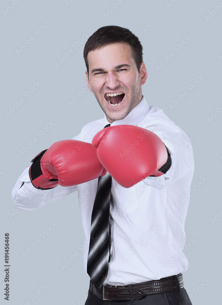 Businessman ready to fight with boxing gloves over gray Businessman ready to fight with boxing gloves over gray