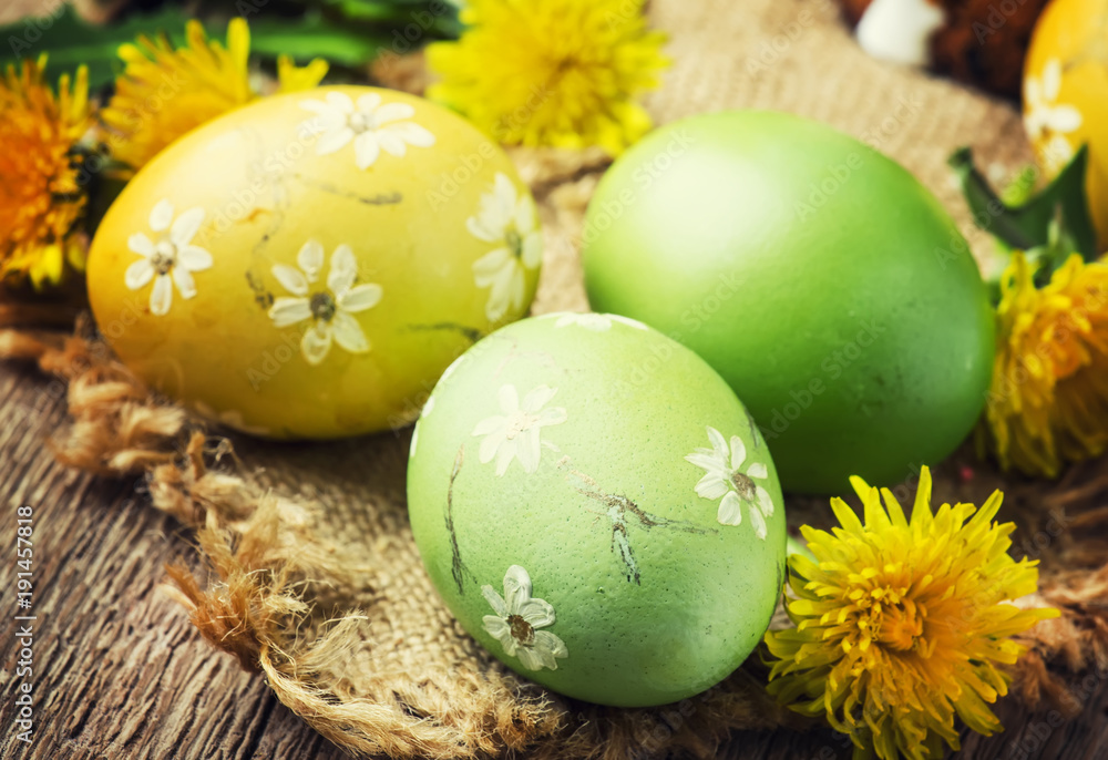 Obraz premium Easter yellow and green eggs with spring dandelions, festive composition in rustic style, vintage wooden background, selective focus
