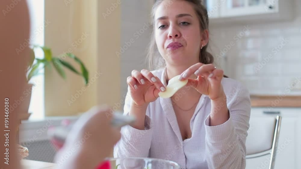 Two girls sit on a table in the kitchen talking Two girls sit on a table in the kitchen talking