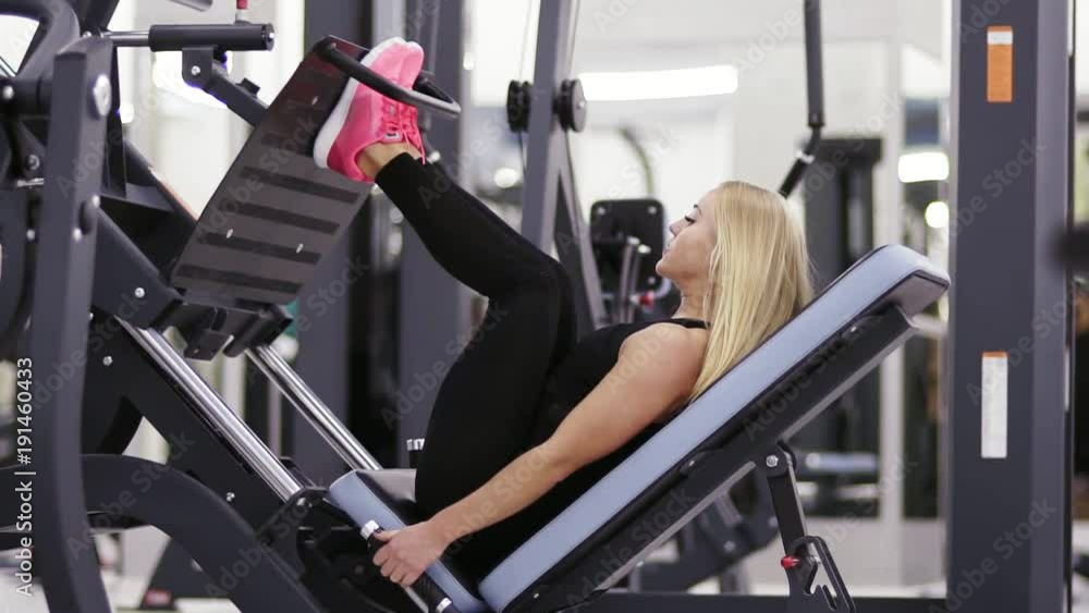 Beautifull sexy girl in black sportswear doing exersices on leg press mashine set at the gym. Heathcare and wellbeing. Beautifull sexy girl in black sportswear doing exersices on leg press mashine set at the gym. Heathcare and wellbeing.