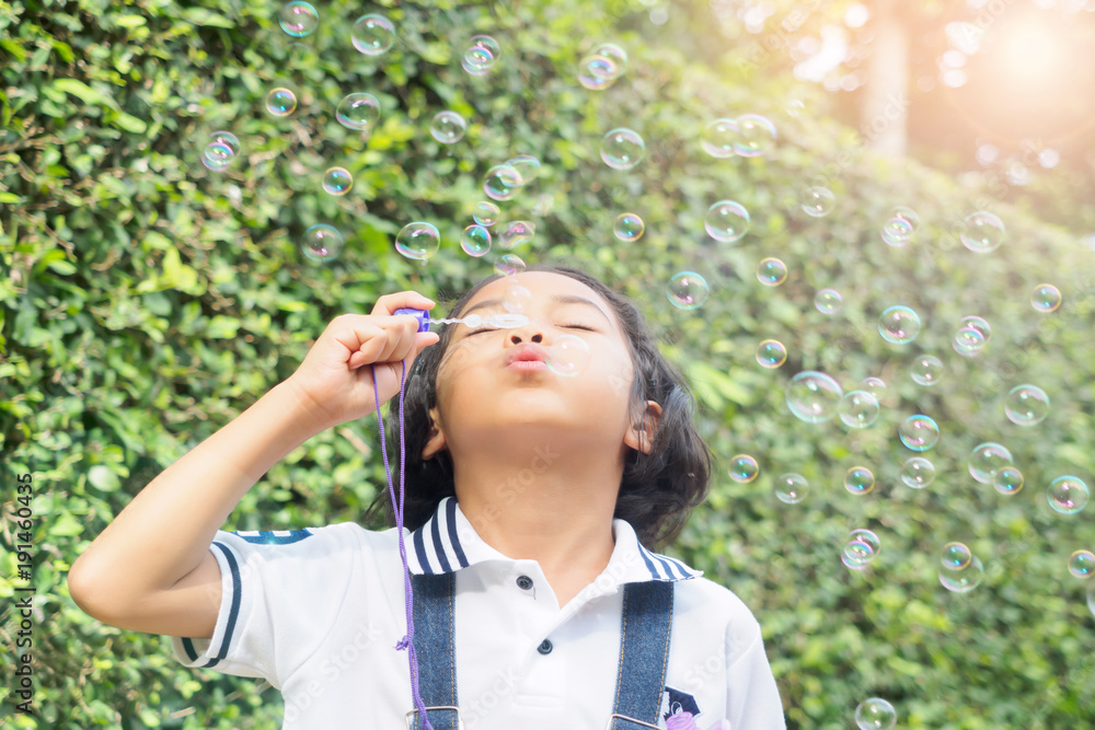 Asian girls blowing bubbles happily in the park.female,children Asian girls blowing bubbles happily in the park.female,children
