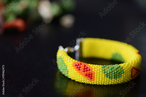 Bright yellow bracelet with citrus print on a dark background close up