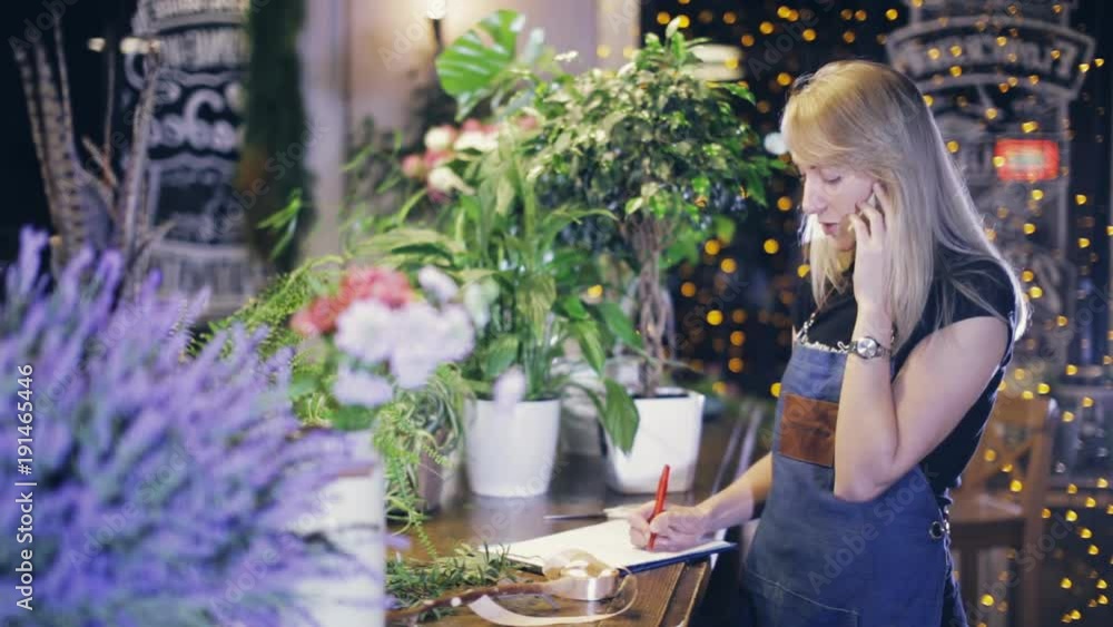 girl florist talking on the phone and writing girl florist talking on the phone and writing