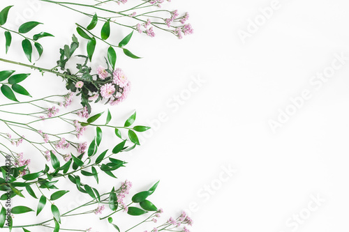Flowers composition. Frame made of pink flowers and green leaves on white background. Flat lay, top view, copy space