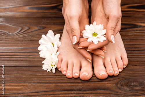cropped view of female hands and feet with medicine and pedicure on wooden surface
